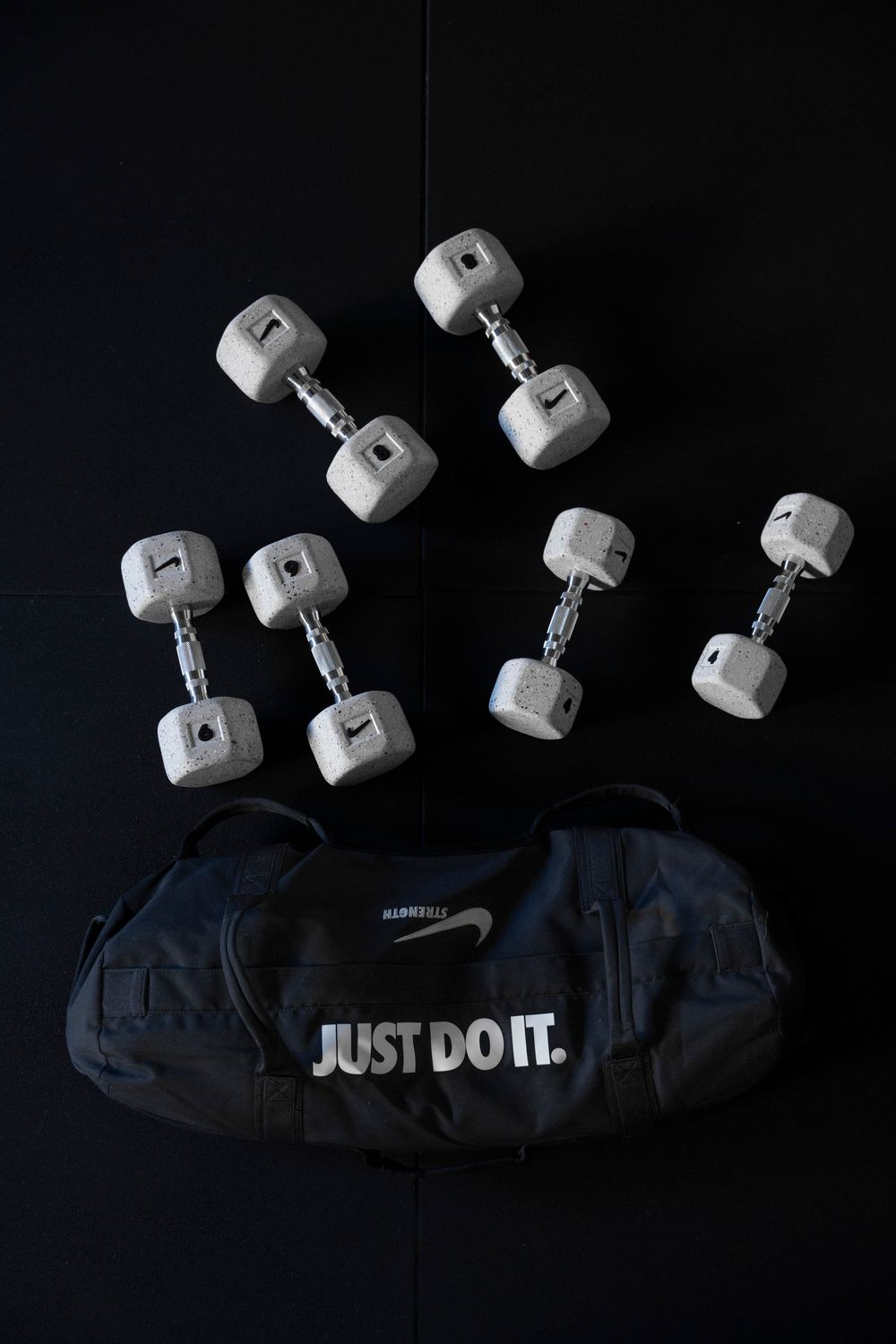 Overhead shot of several small chrome dumbbells and a black eye mask; wellness and home workout accessory photography.