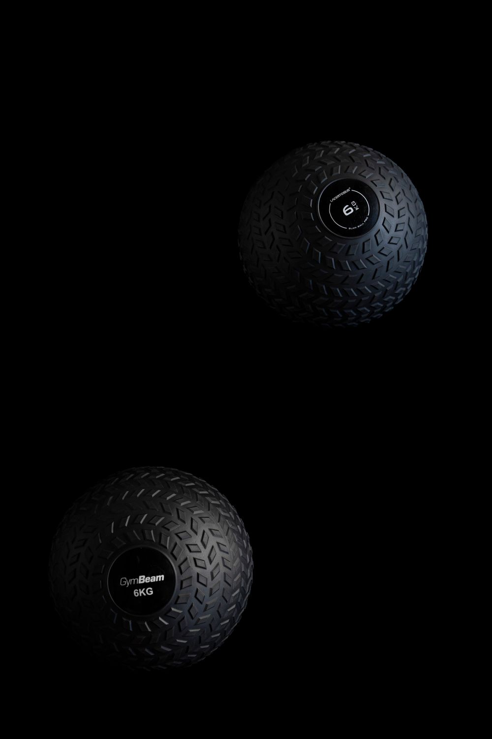 Two black medicine balls on a dark textured floor; minimalist fitness equipment and studio branding.