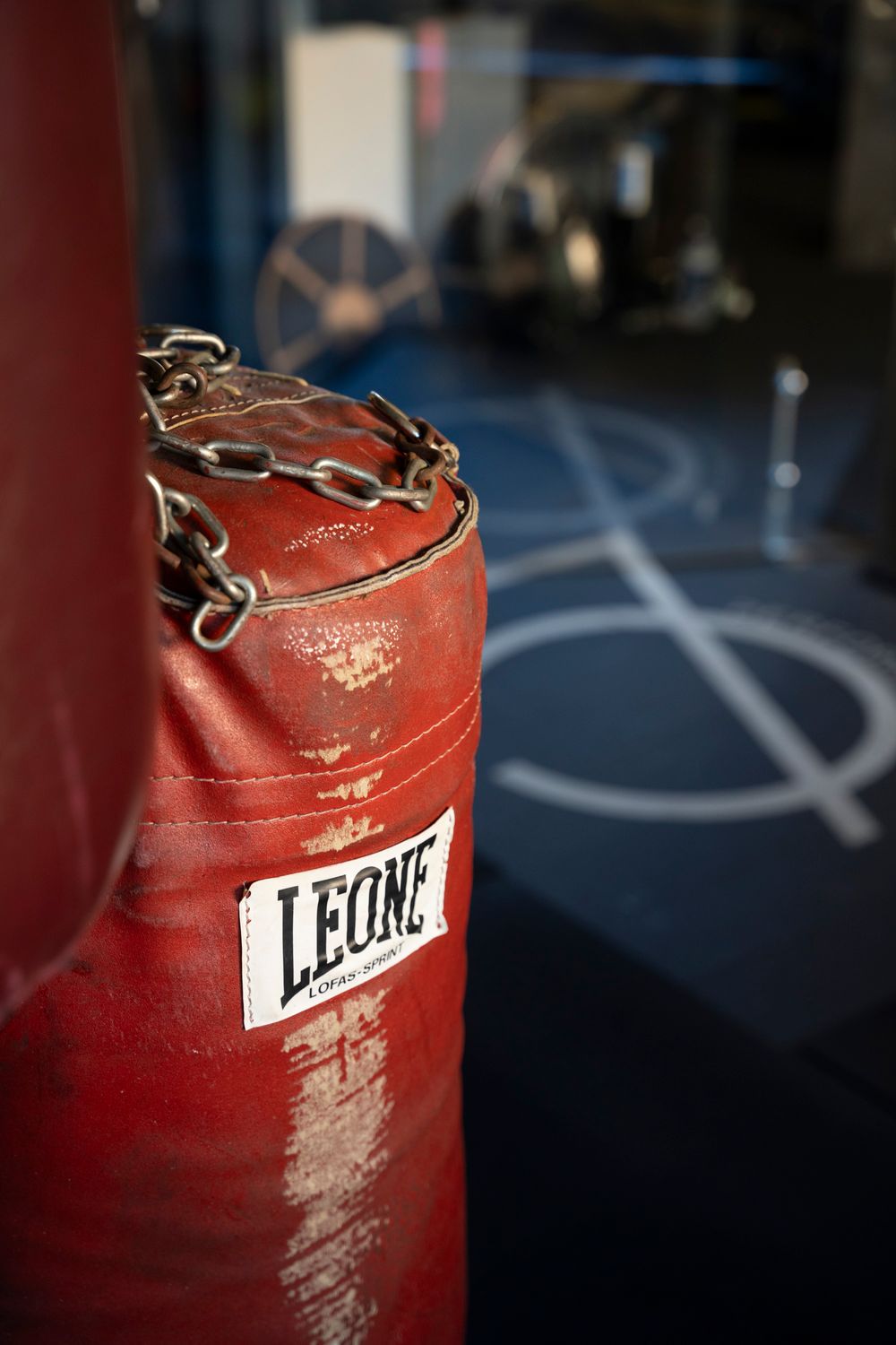 Close-up of a red leather Leone boxing bag in a professional gym; lifestyle fitness and combat sports photography.