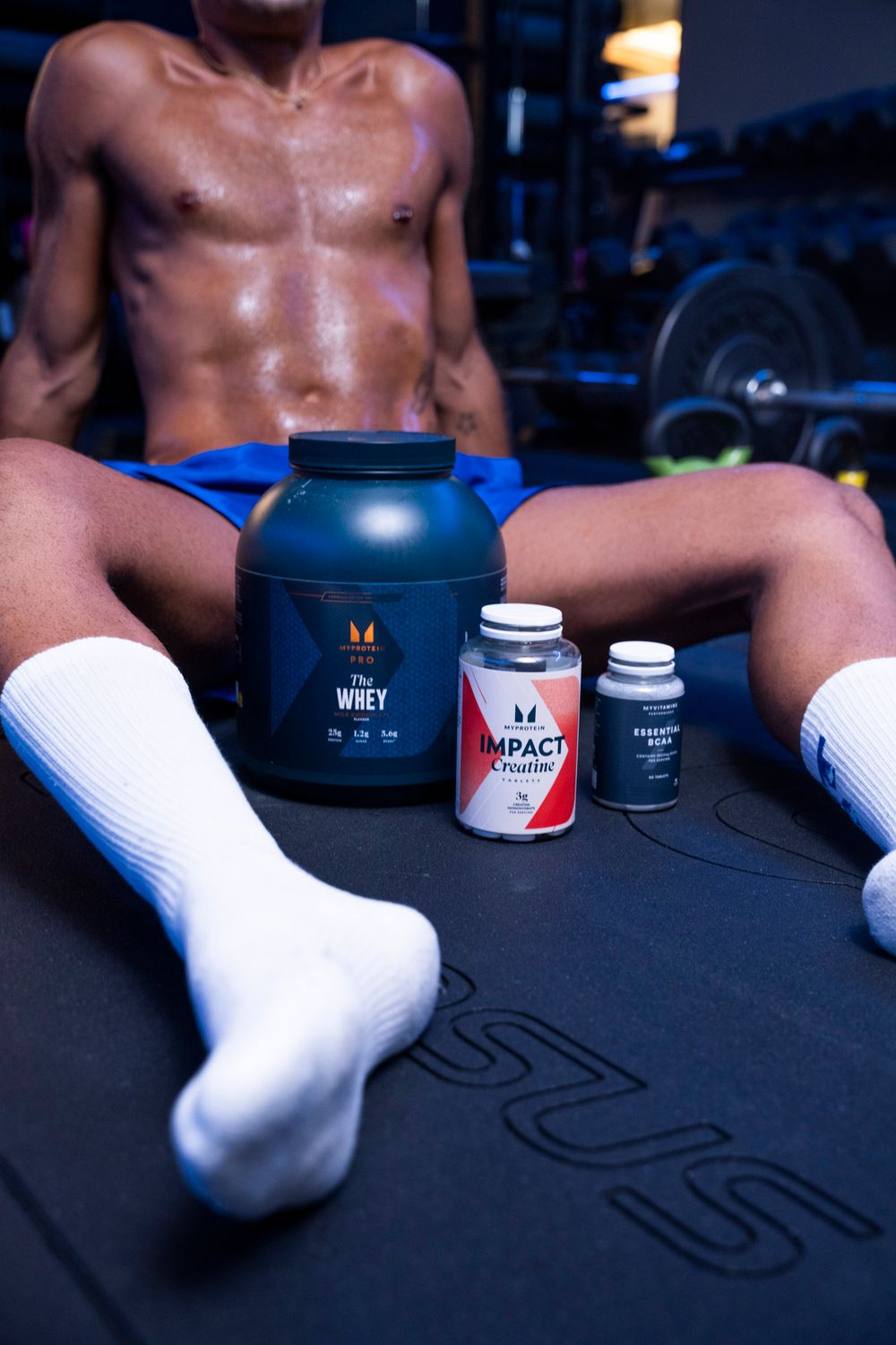 Low-angle shot of a person sitting with fitness supplements in a gym; authentic athletic lifestyle content.
