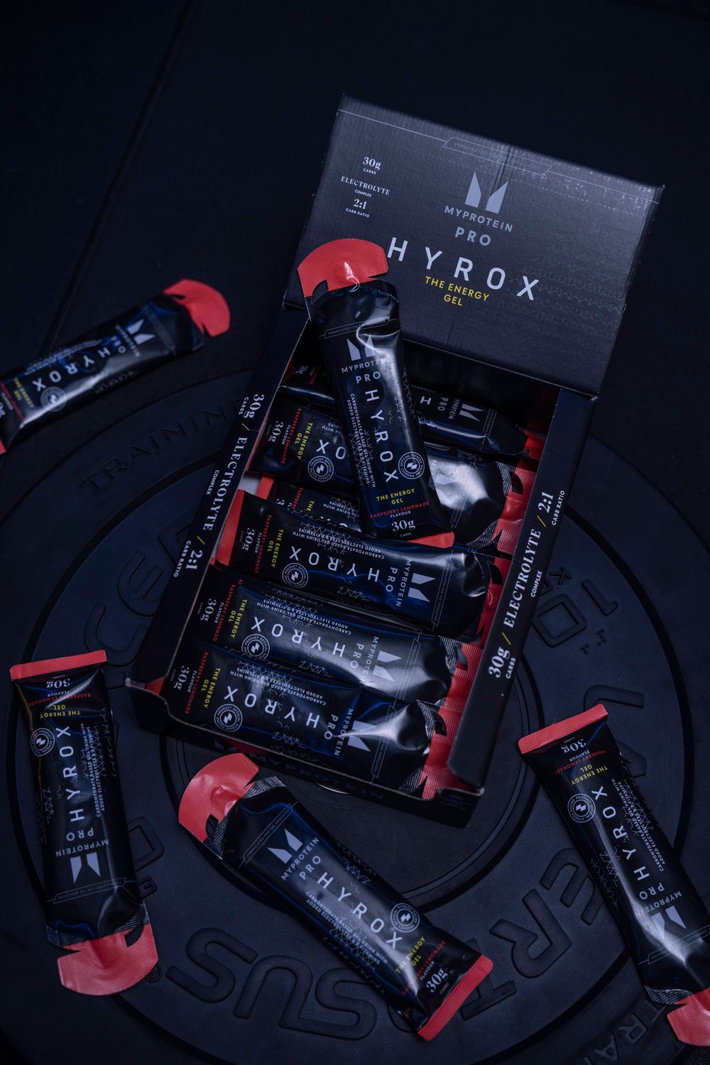 Flat lay of fitness supplement packets on a dark textured surface; creative product display for wellness labels.