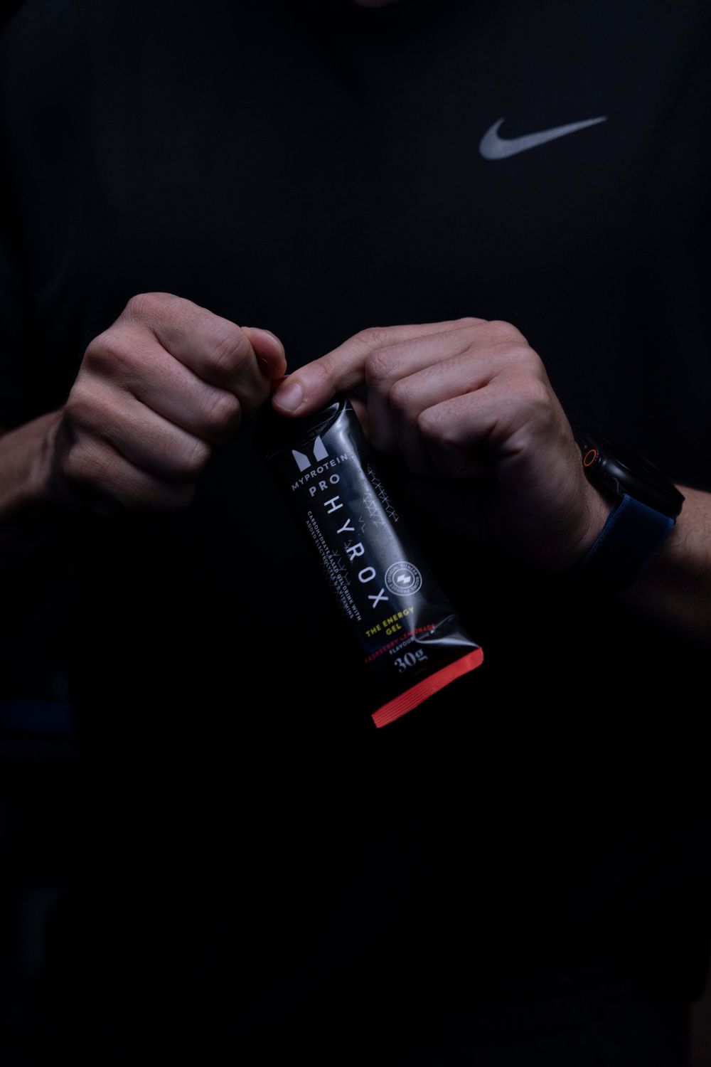 Close-up of hands holding a fitness supplement bar in dramatic lighting; product-focused e-commerce imagery.