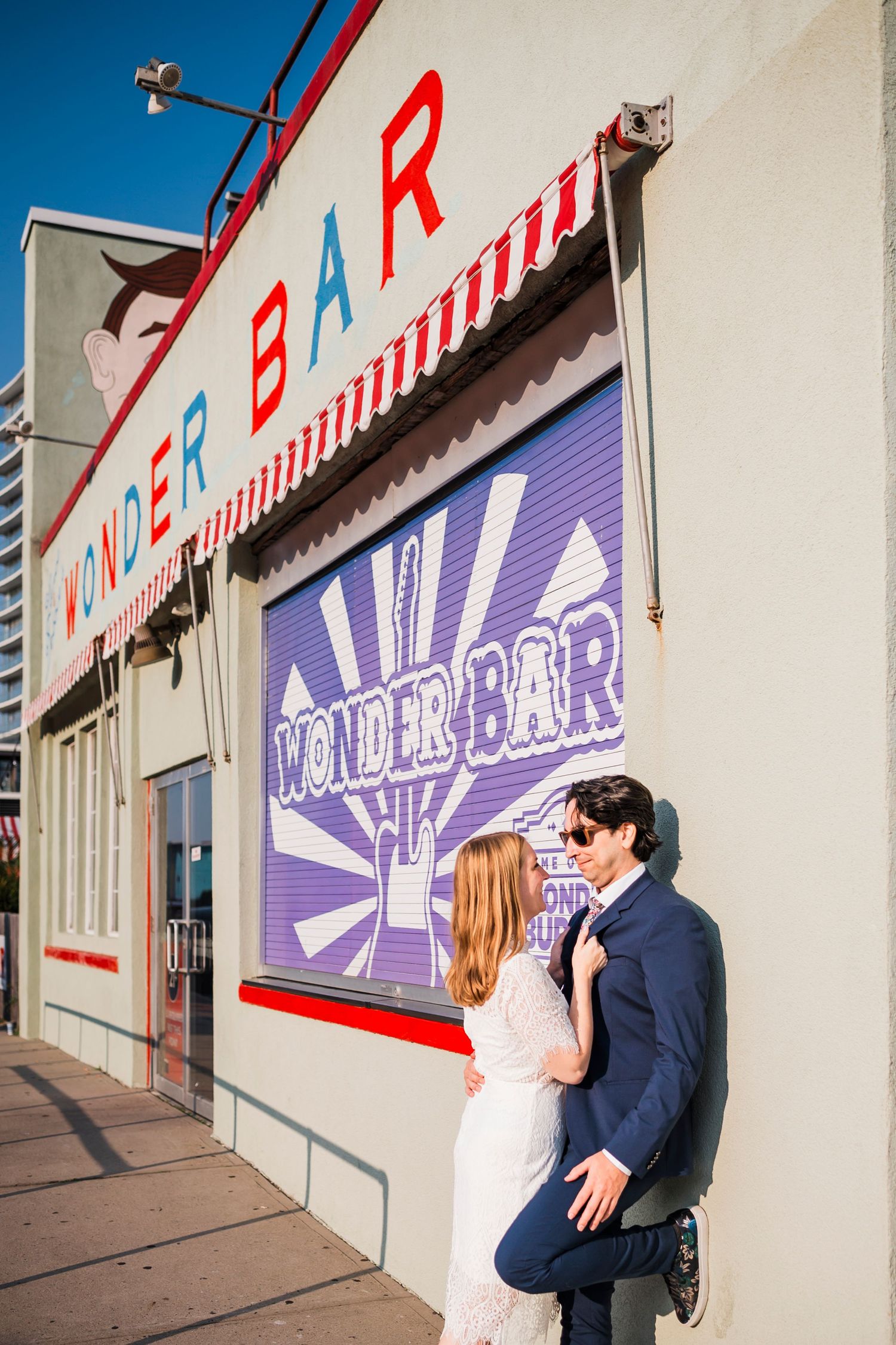 A couple shares an intimate moment against an urban wall with colorful signage and graphics.