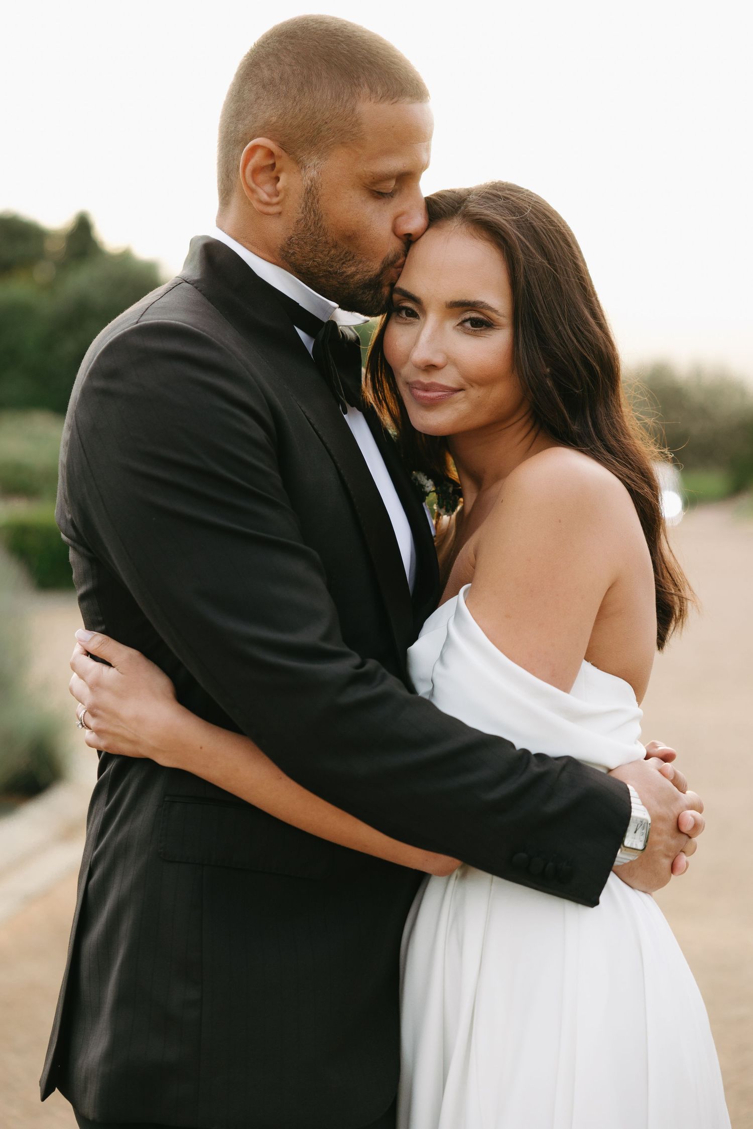 A romantic wedding photo series shows a couple embracing on a beach during sunset in formal attire.