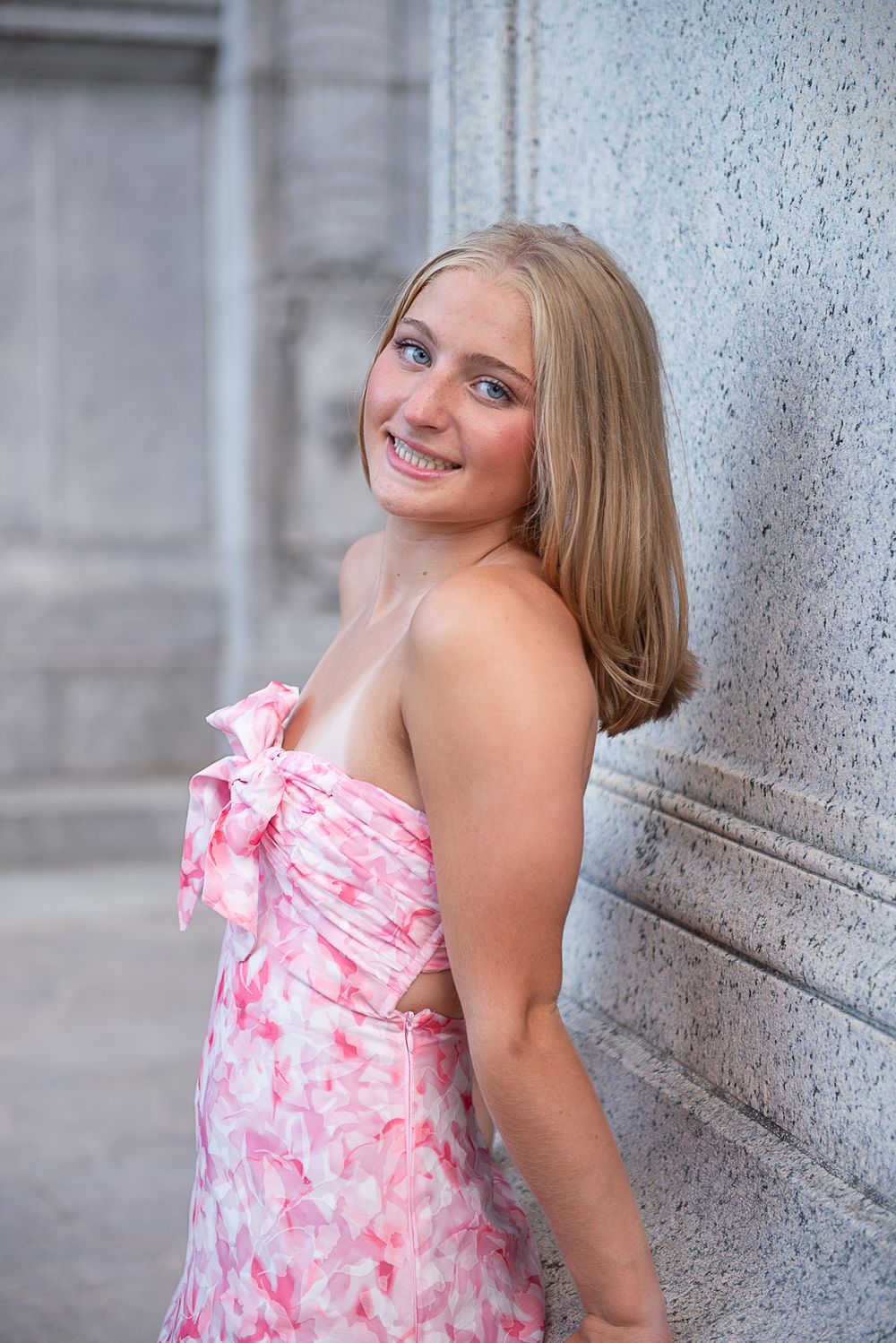 A series of four photos showing someone in a pink and white floral dress posing against a textured gray wall.