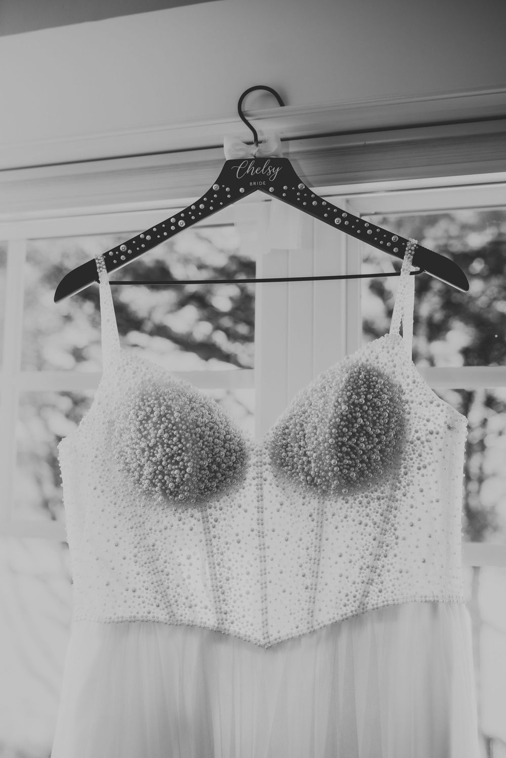 A series of white wedding dresses with sparkly beaded bodices hanging on hangers in a bridal shop.