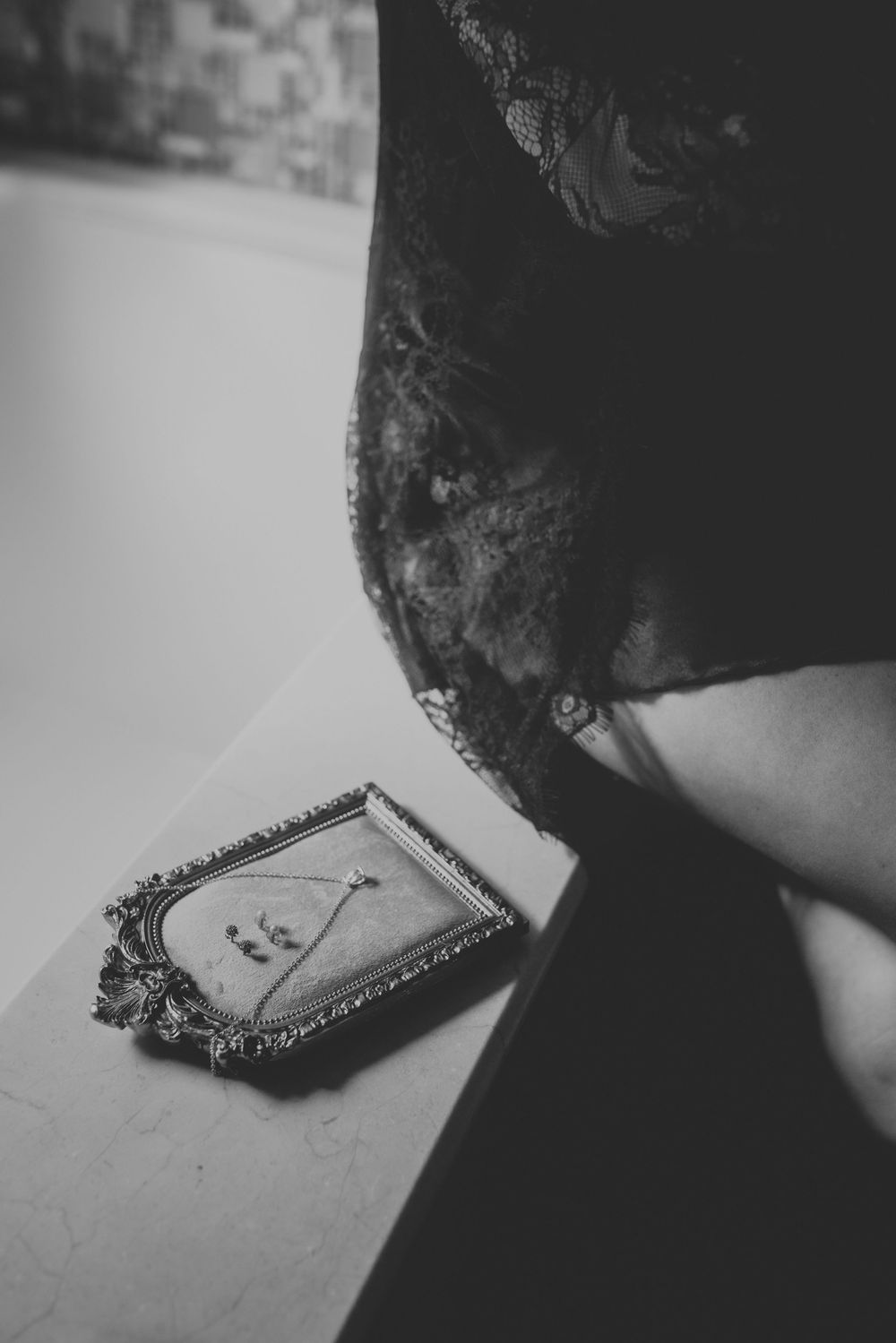 A black and white photograph showing an ornate vintage picture frame on a surface next to dark fabric.