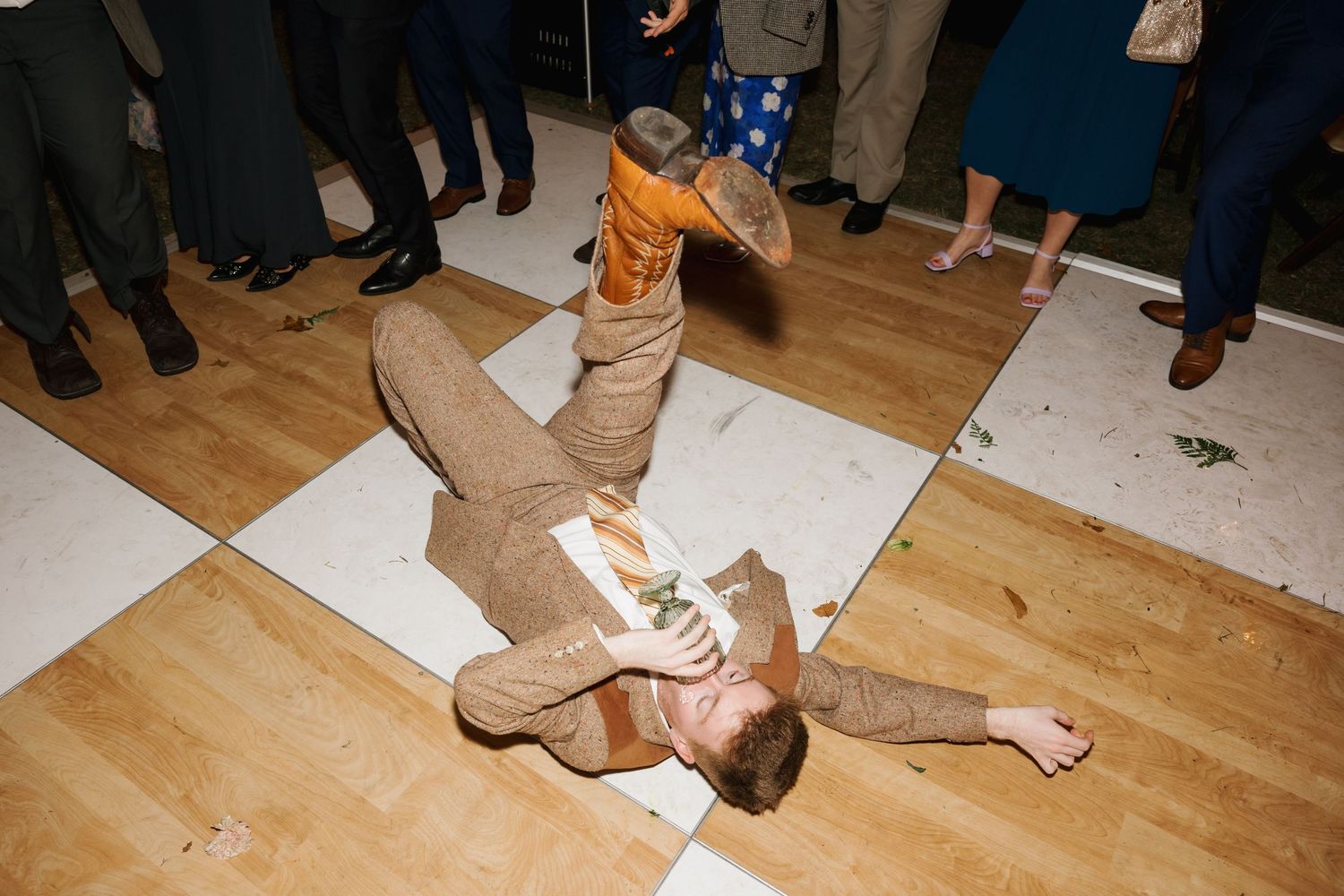 A dancer performs an energetic breakdancing move on a wooden floor at a celebration.