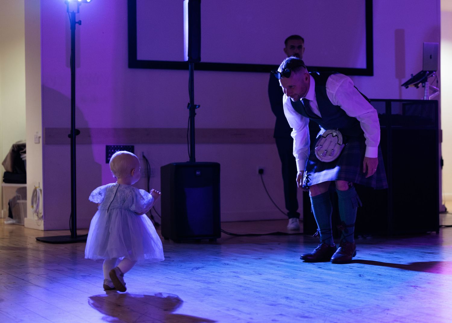Dancers perform energetic moves on a dance floor illuminated by blue lighting during a celebration.