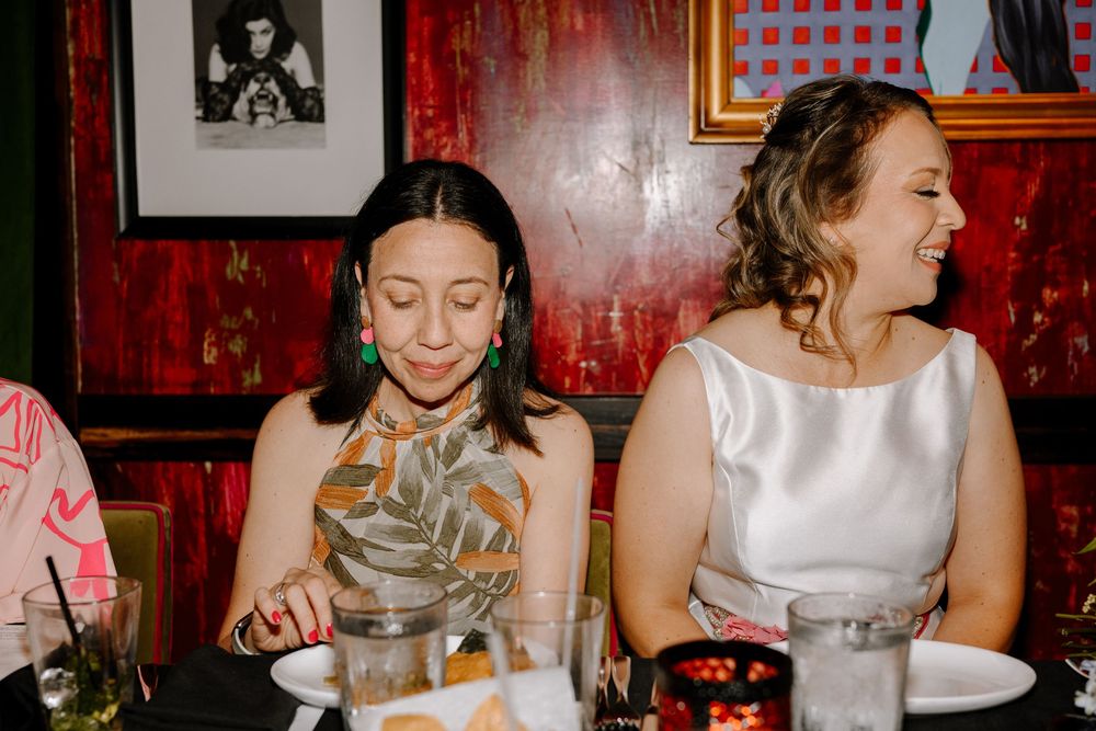 Guests dining at a restaurant with red walls decorated with vintage photographs and artwork.