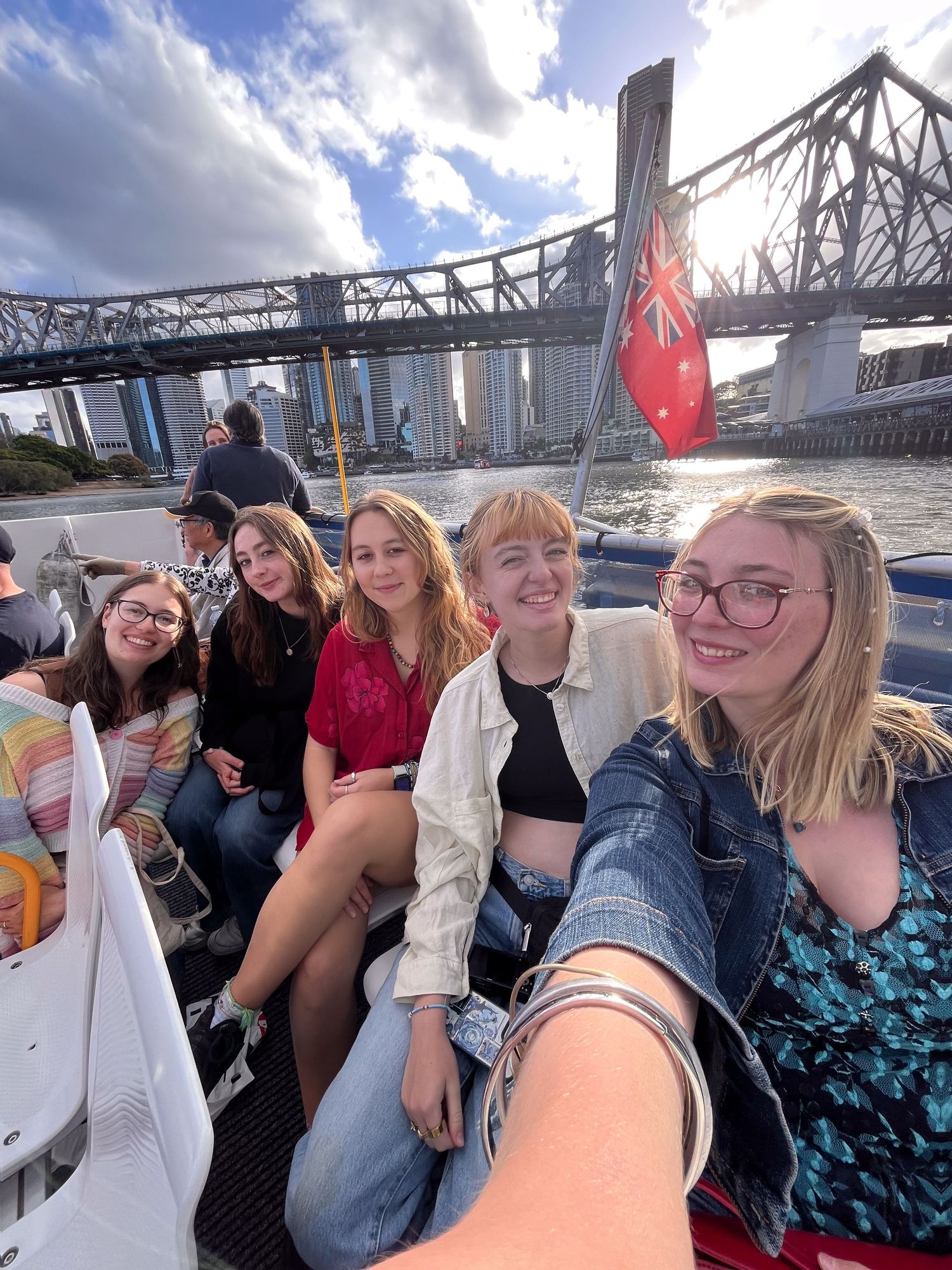 A group enjoying a sunny boat ride along the Brisbane River with the Story Bridge visible in the background.