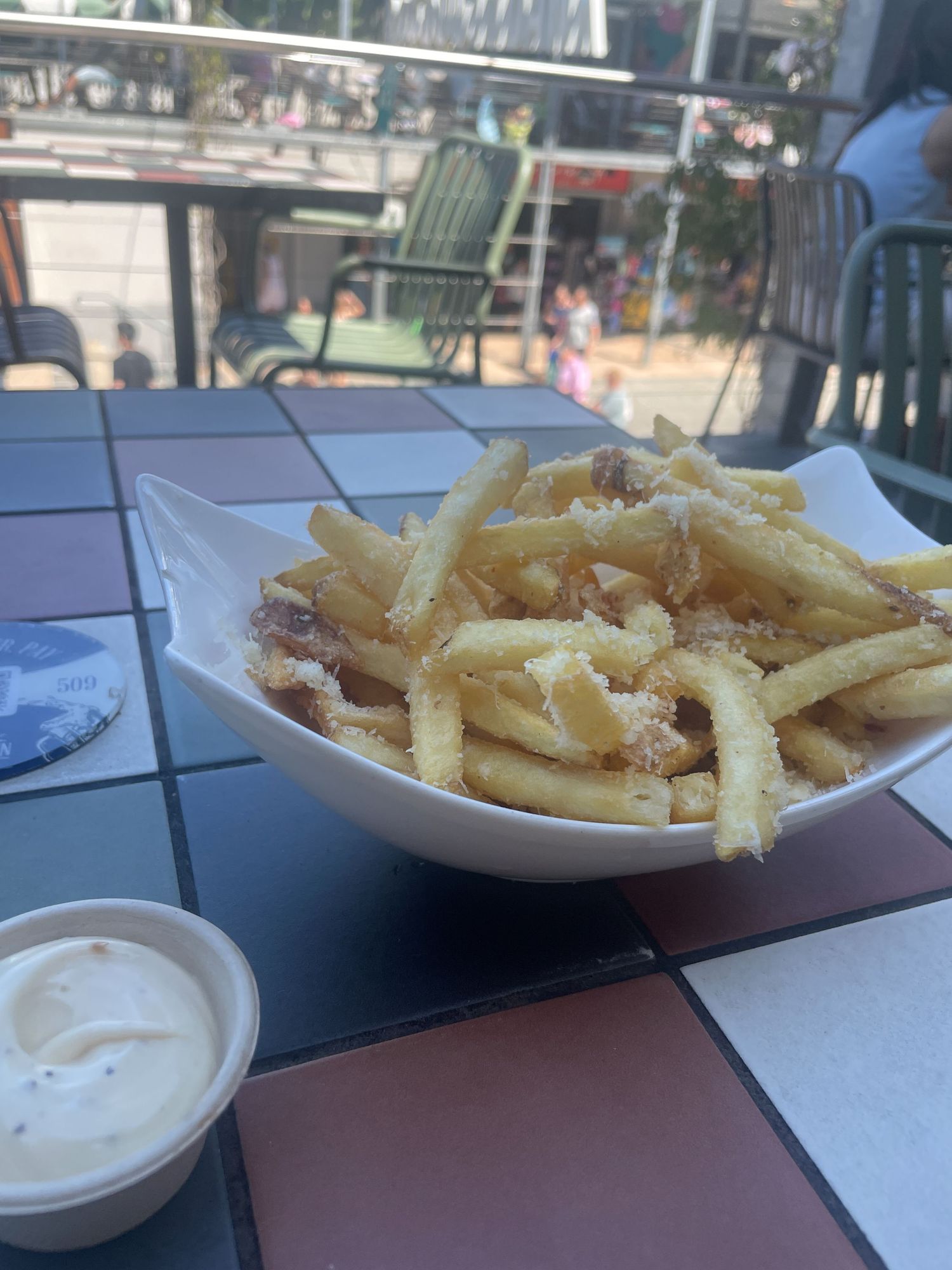 A plate of crispy french fries served with a side of creamy dipping sauce on a restaurant table.