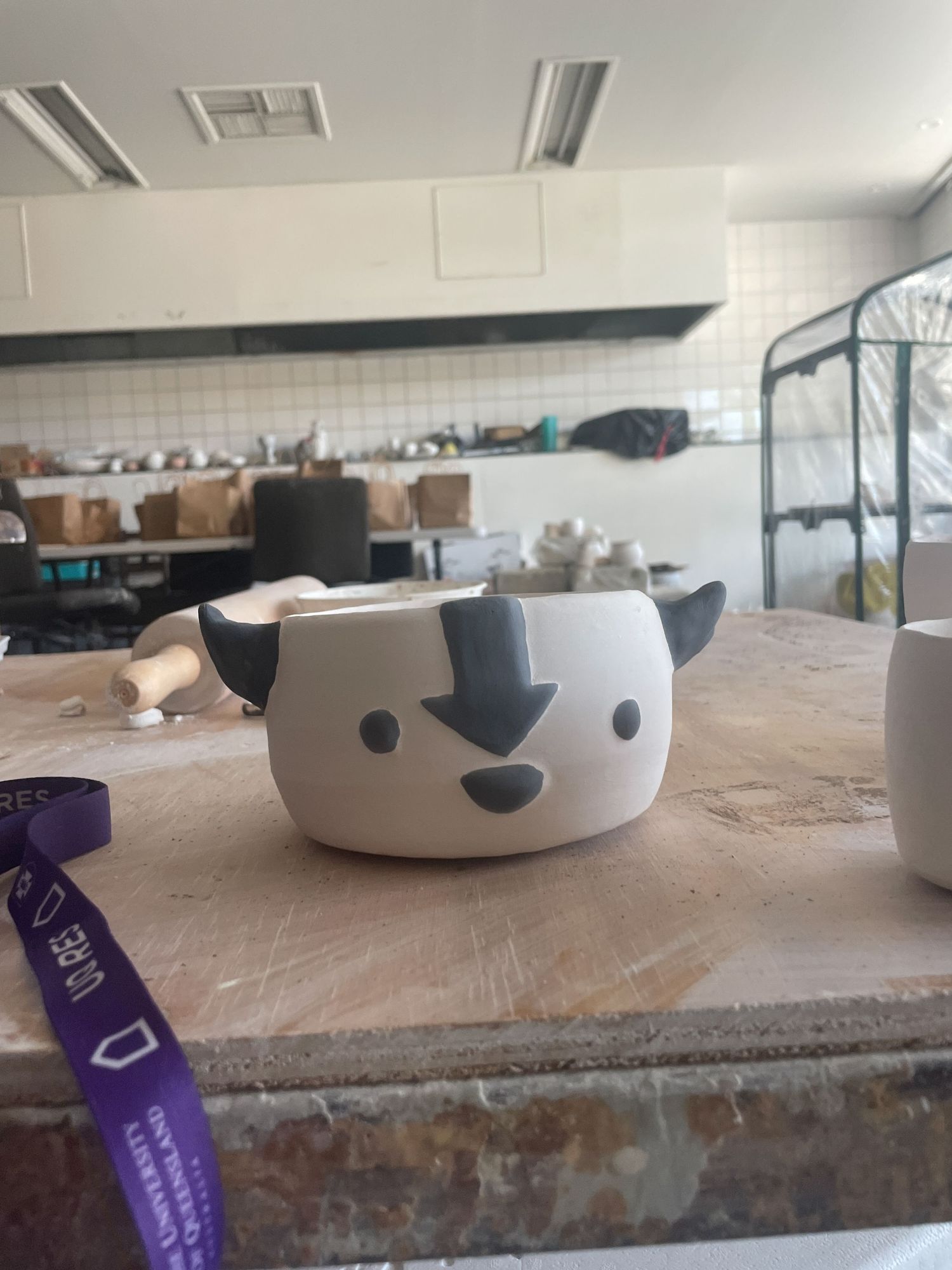 Multiple white ceramic bowls with cute animal faces painted on them sit on a rustic wooden surface.