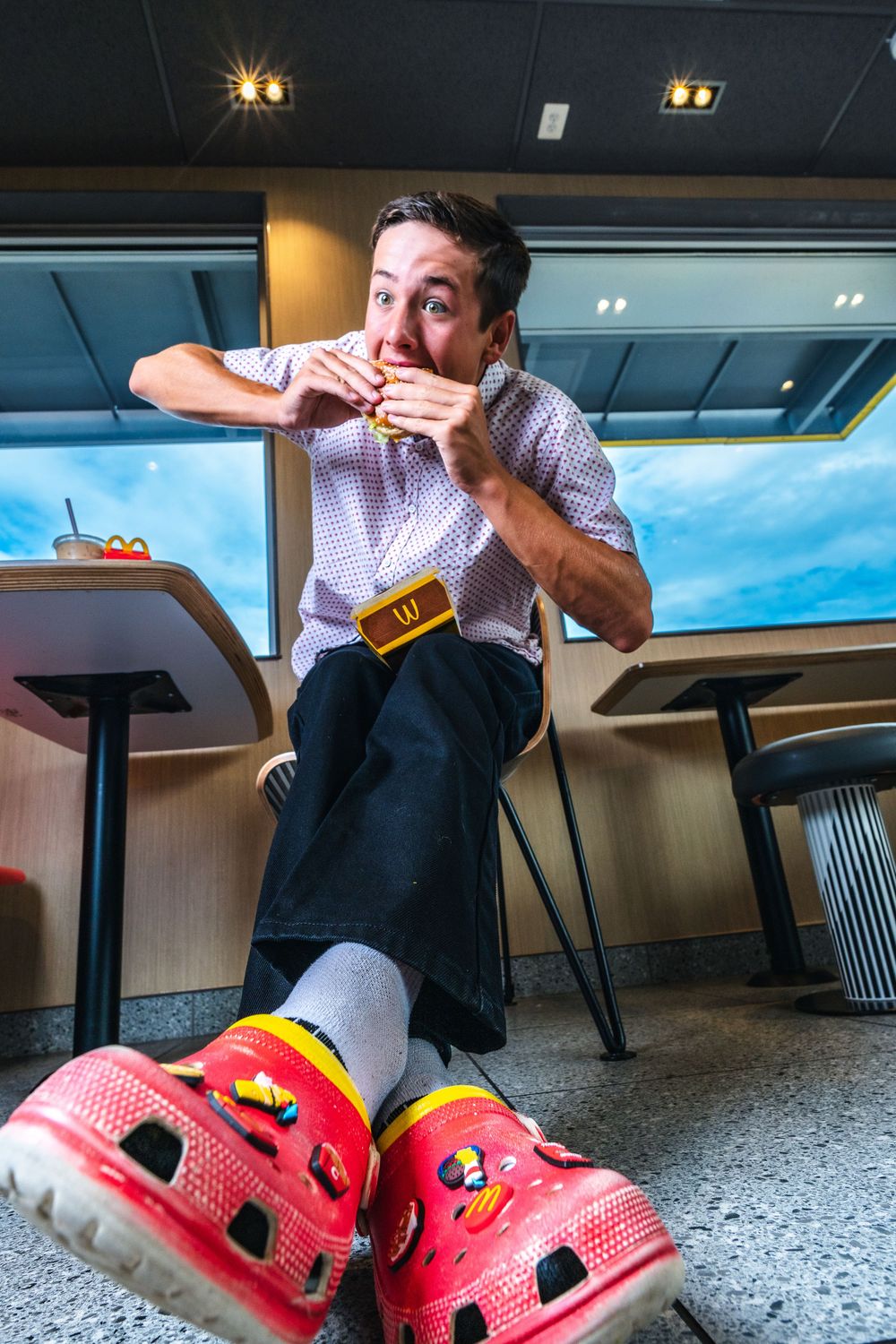 A sequence of photos showing someone drinking beer while wearing bright red Crocs shoes in an indoor setting.
