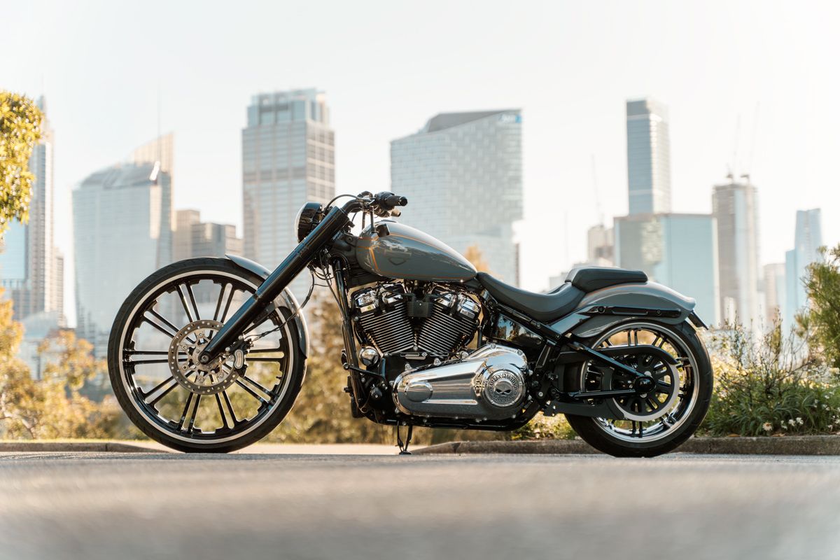 Harley motorcycle parked against urban skyline backdrop during golden sunset hour with city buildings in background photoshoot