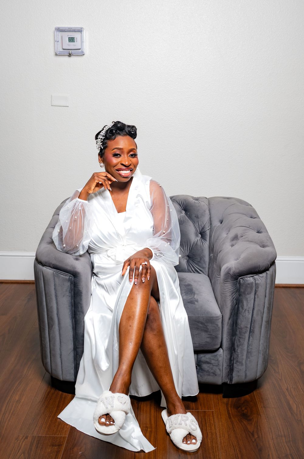 Fashion photoshoot on grey couch featuring white robe and stylish poses.