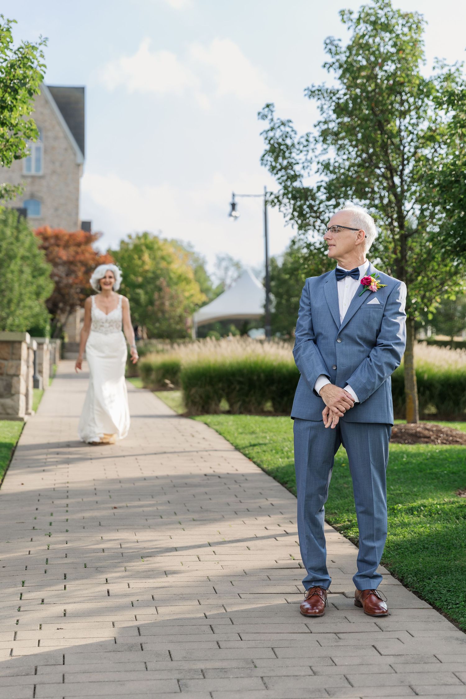 Bride walking to the groom along a stone path surrounded by lush greenery at Vineland Estates Winery.