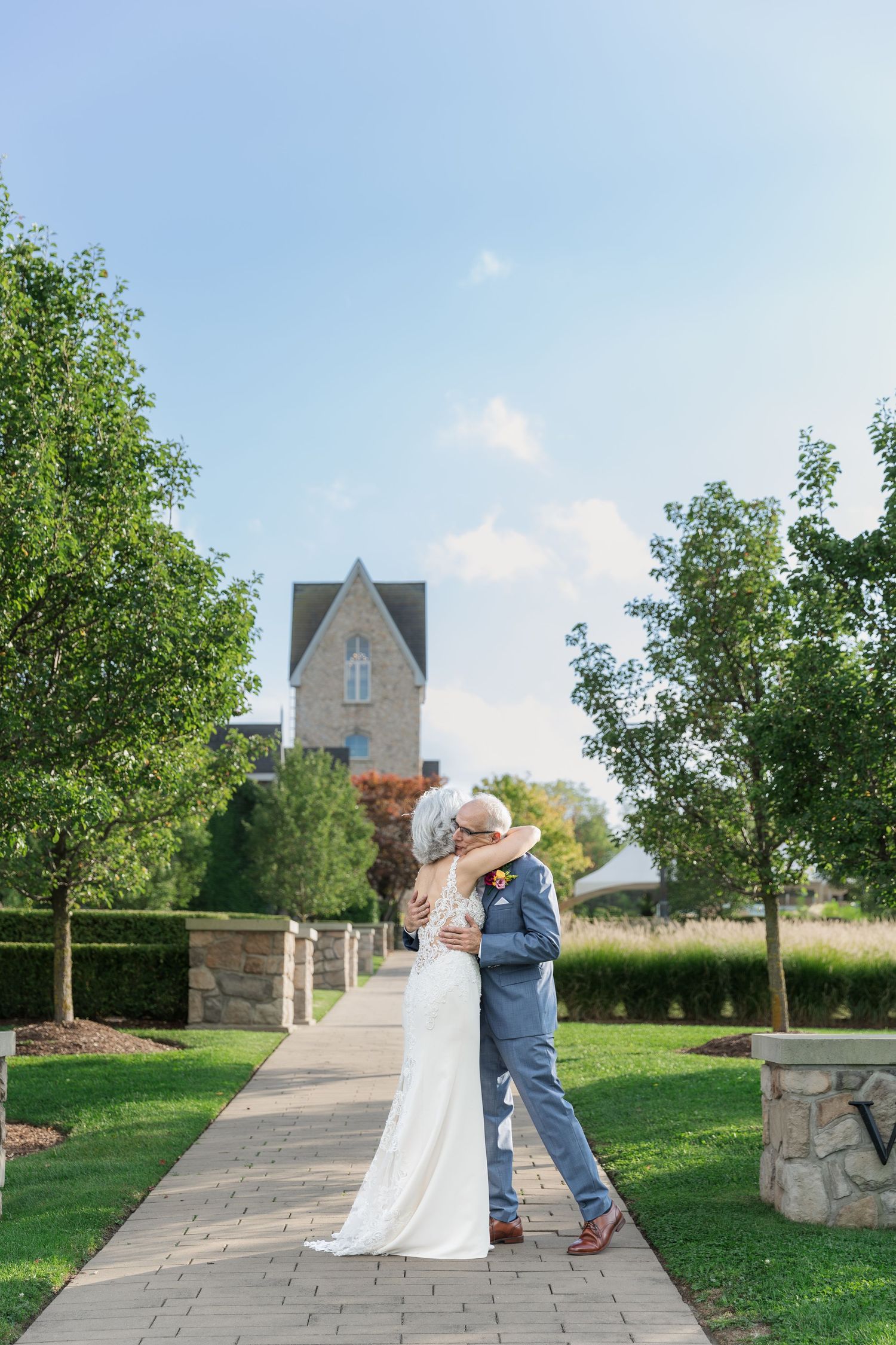 Bride and groom share an embrace during their first look surrounded by lush greenery at Vineland Estates Winery.