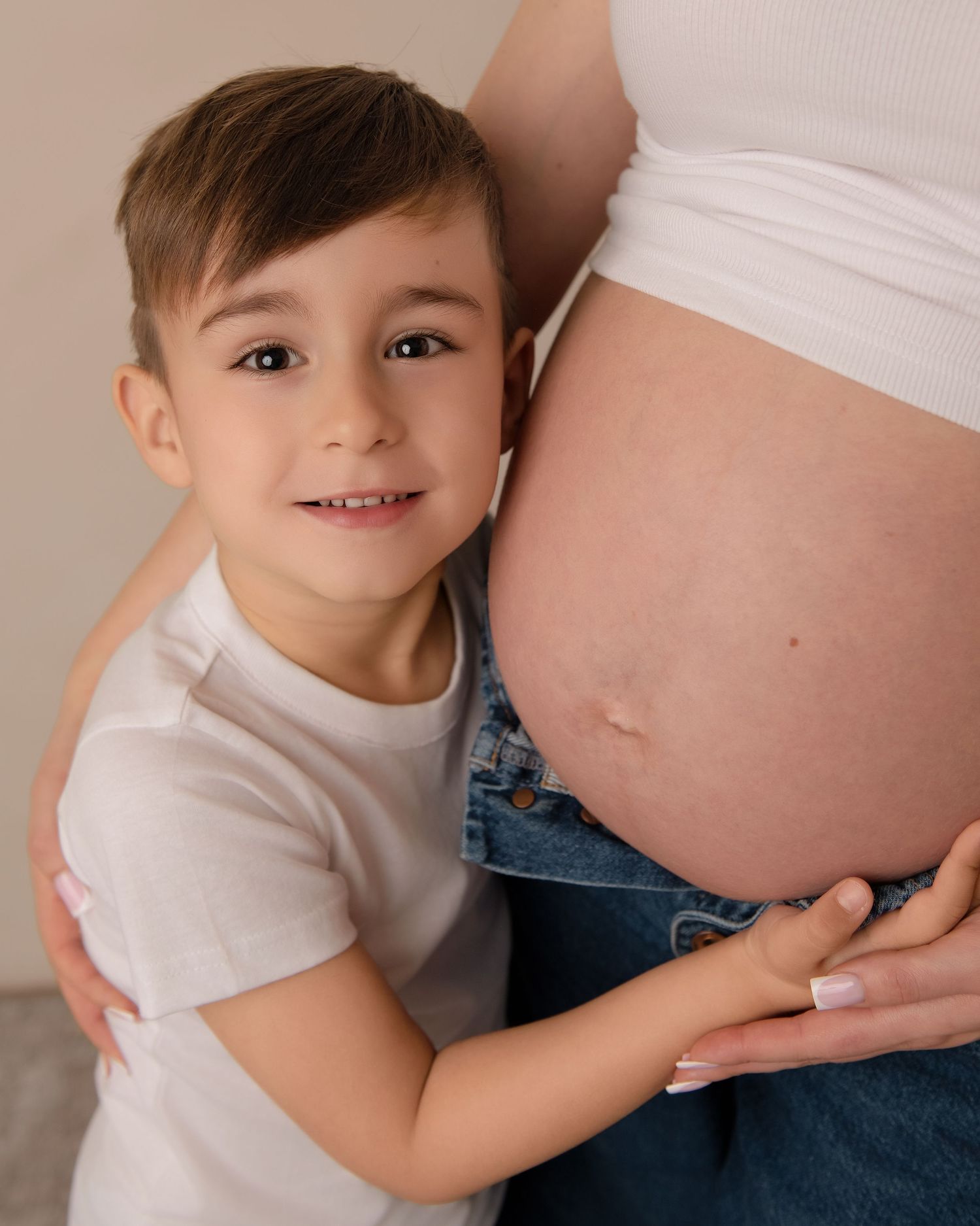 A young child smiles in a relaxed family maternity photography session.