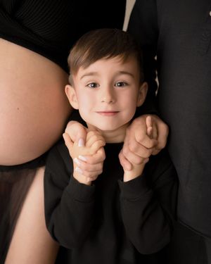 A young child smiles in a relaxed family maternity photography session.