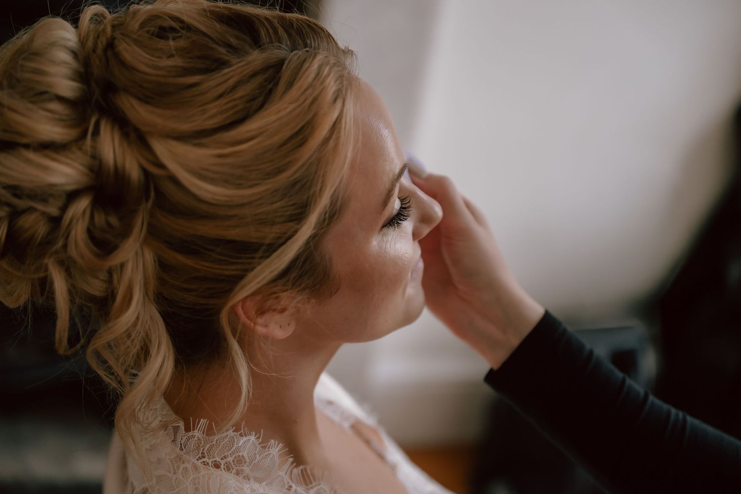 Close-up view of an elegant Bridal updo hairstyle with soft curls and wispy tendrils framing the face.