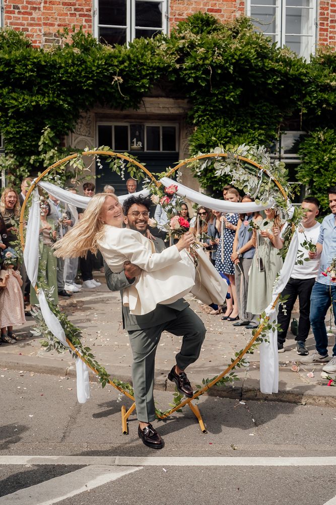 Wedding guests create a tunnel with floral garlands and white fabric for the newlyweds to run through during the celebration.