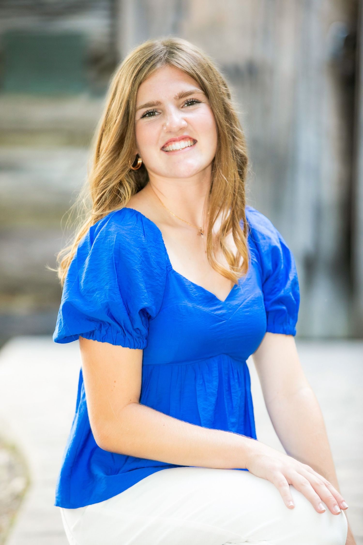 A woman in a vibrant royal blue dress poses outdoors with a bright smile in a series of portrait photos.