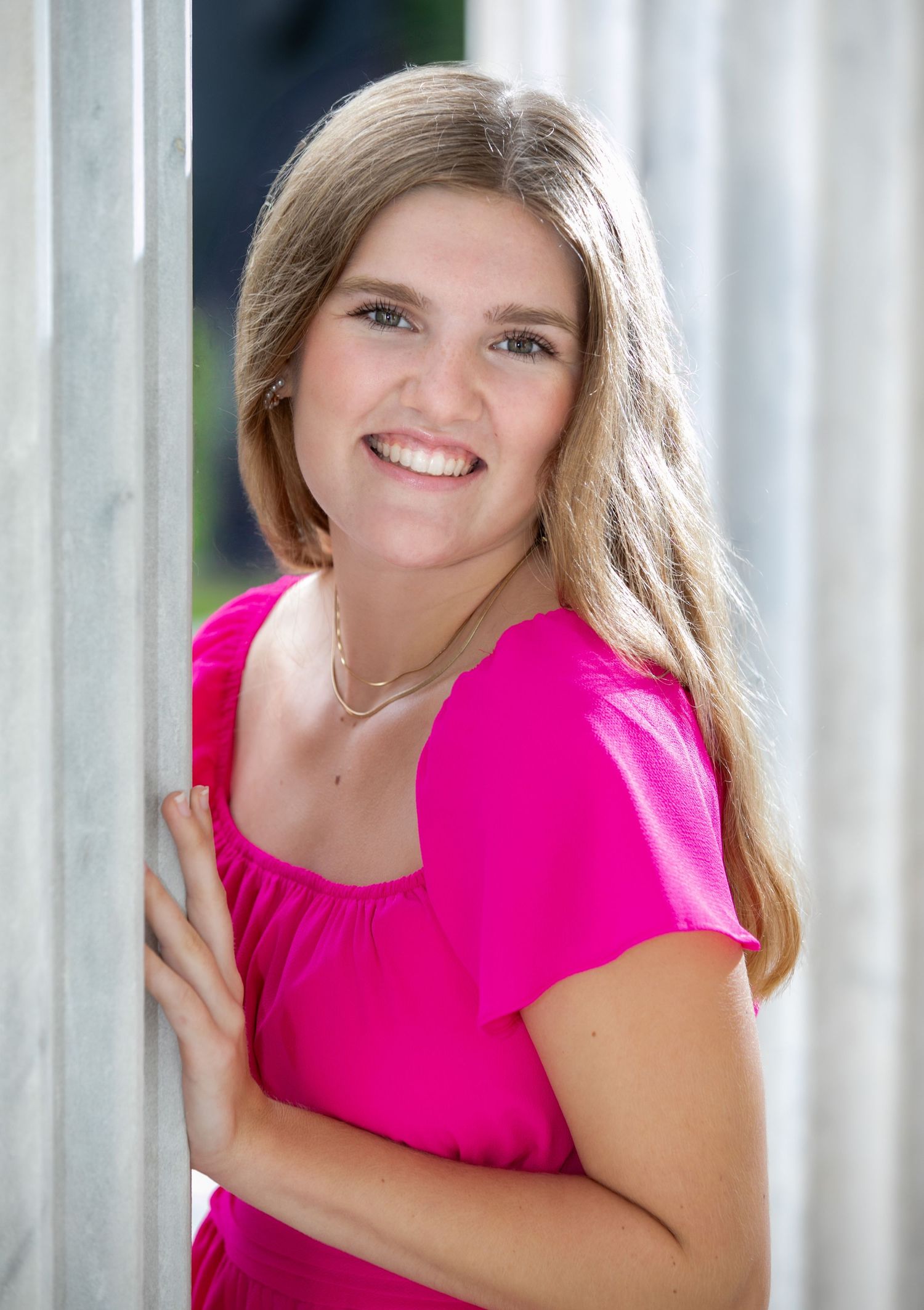 A person in a bright pink sleeveless top poses against a light background with a warm smile.