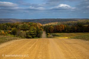 Wide panoramic view of rolling farmland and distant hills under dramatic cloudy skies.