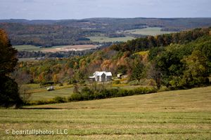 Sweeping vista of rural farmland with rolling hills and autumn colors stretching to the horizon.