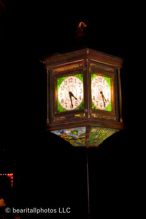 Illuminated vintage clock lantern glowing against dark night sky.