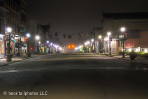 Nighttime view of empty small town main street with street lights creating ambient glow.