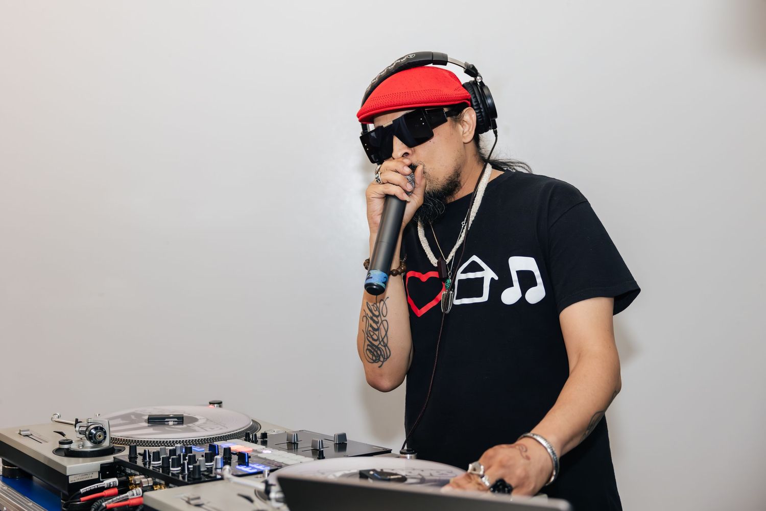 DJ performing at a turntable setup with mixing equipment and headphones in a professional setting.