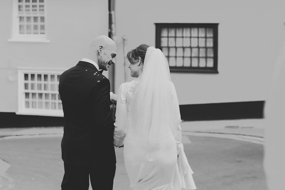 A tender wedding moment captured in black and white outside a white building.