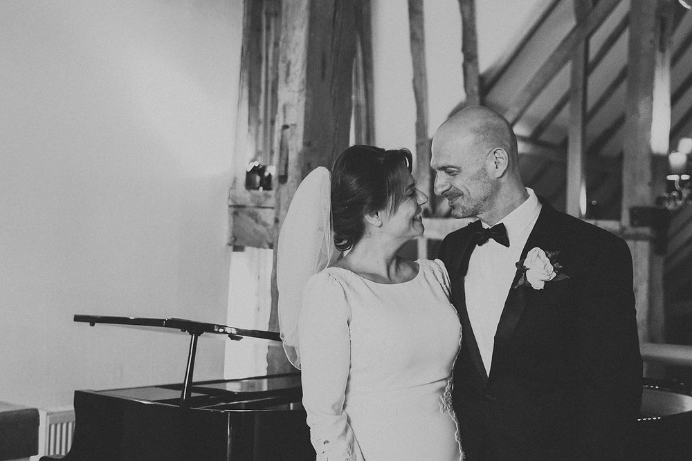 A romantic black and white photo of newlyweds sharing an intimate moment indoors.