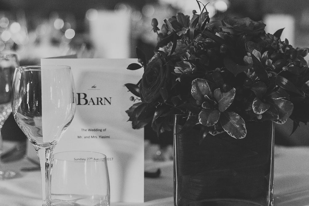 Black and white detail shot of wedding reception table with wine glass and floral centerpiece.
