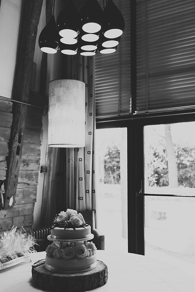 Wedding cake displayed under modern lighting in rustic venue setting.