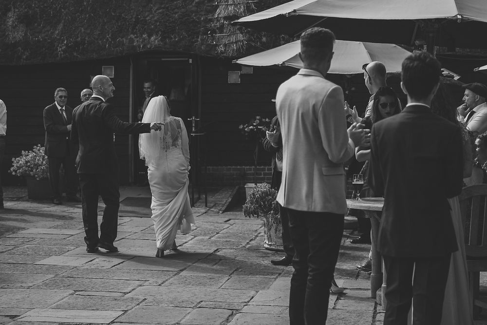 Wedding guests gathered outdoors during a ceremony in black and white.