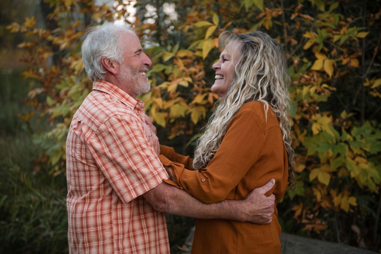 A Denver Colorado couple embraces in a romantic autumn setting with golden leaves in the background.