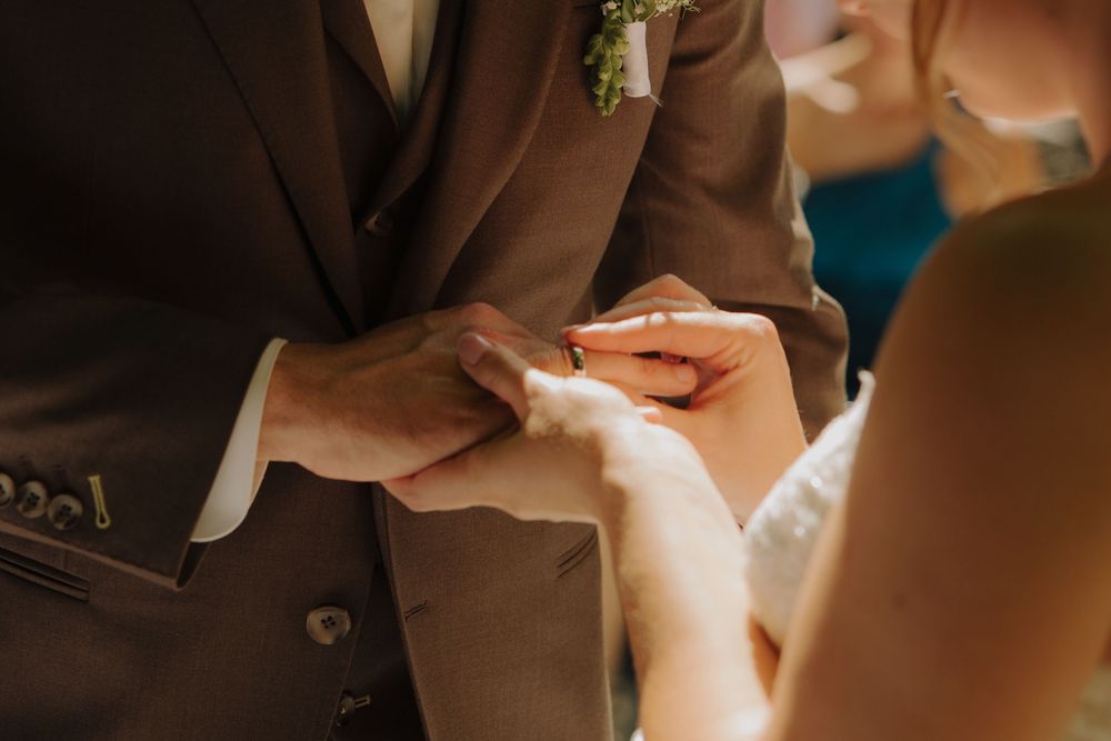 A bride and groom hold hands during their wedding ceremony in a romantic indoor setting.
