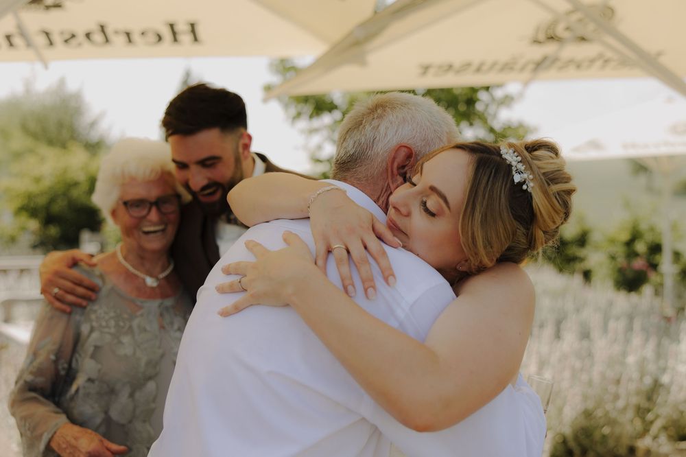 Emotional wedding scene showing tender embraces between family members during an outdoor ceremony.