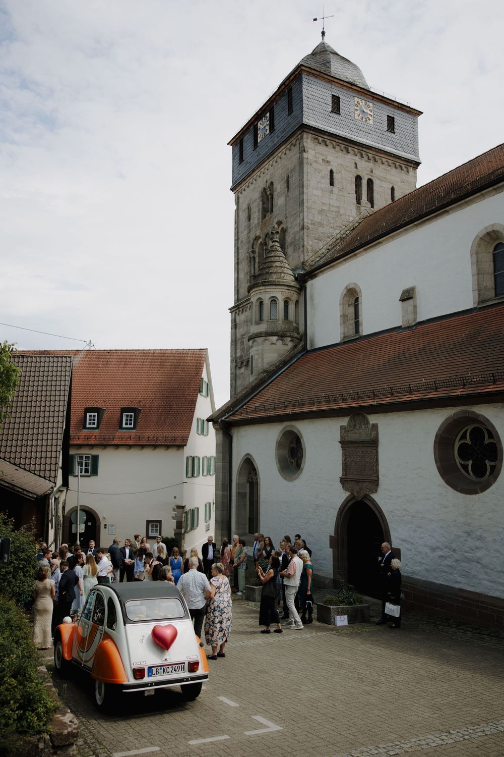 A series of exterior shots showing a traditional white church building with people gathering outside for a wedding celebration.