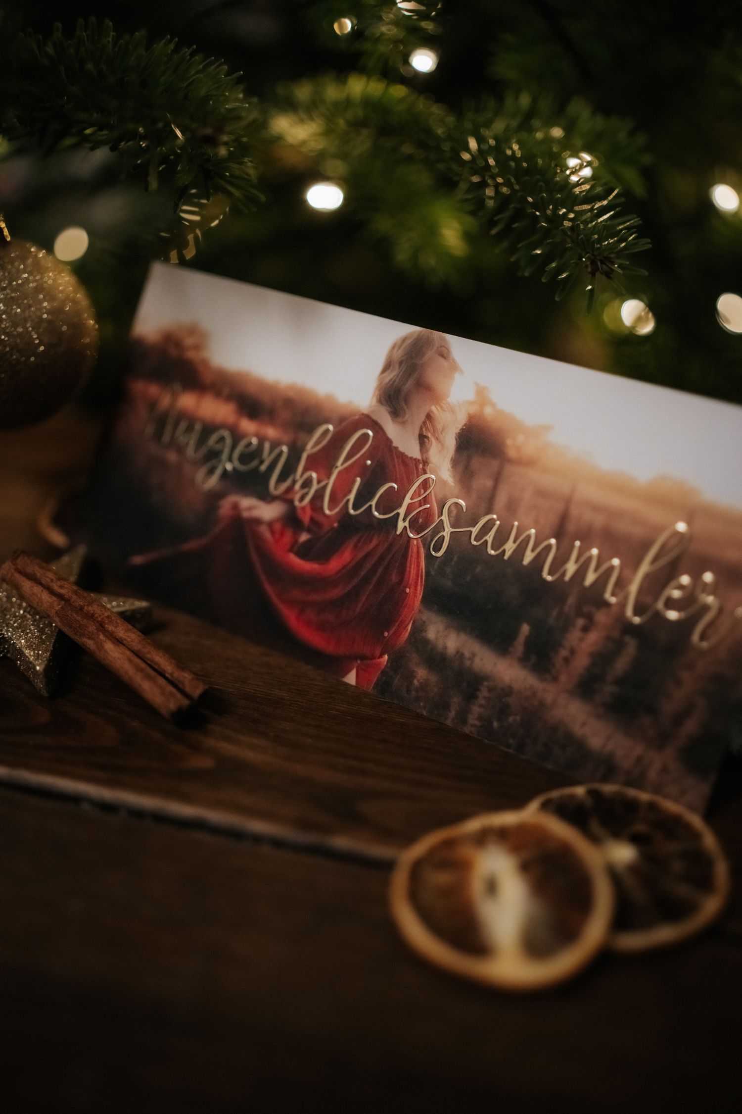 A photograph displayed near Christmas decorations with cinnamon sticks and wedding rings on a dark wooden surface.