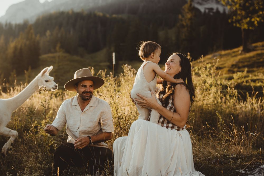 A loving family moment captured in golden sunlight against a mountainous backdrop during a sunset photo session.