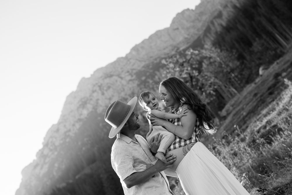 A black and white intimate portrait of a couple sharing a tender moment on a mountain slope.