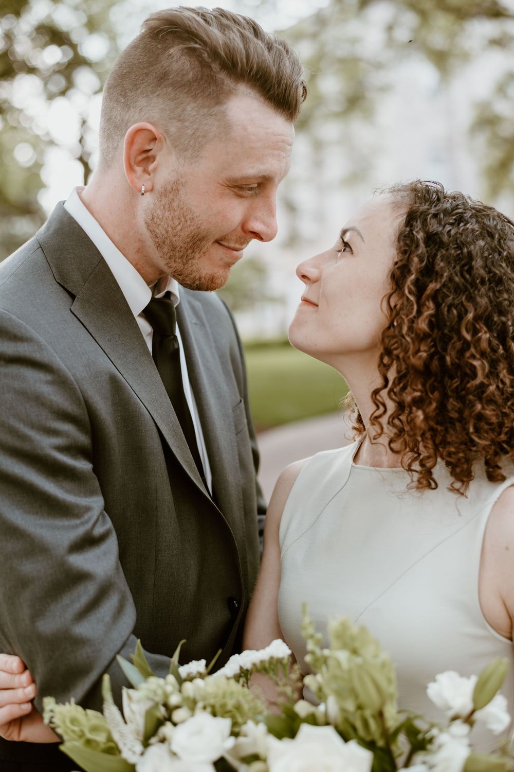 Couple shares an intimate moment at their wedding with flowers in the foreground and soft natural lighting.