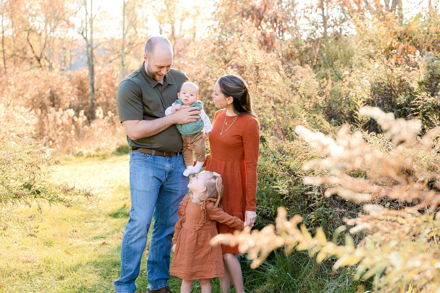 A family shares a joyful moment together in an autumn field with golden light.