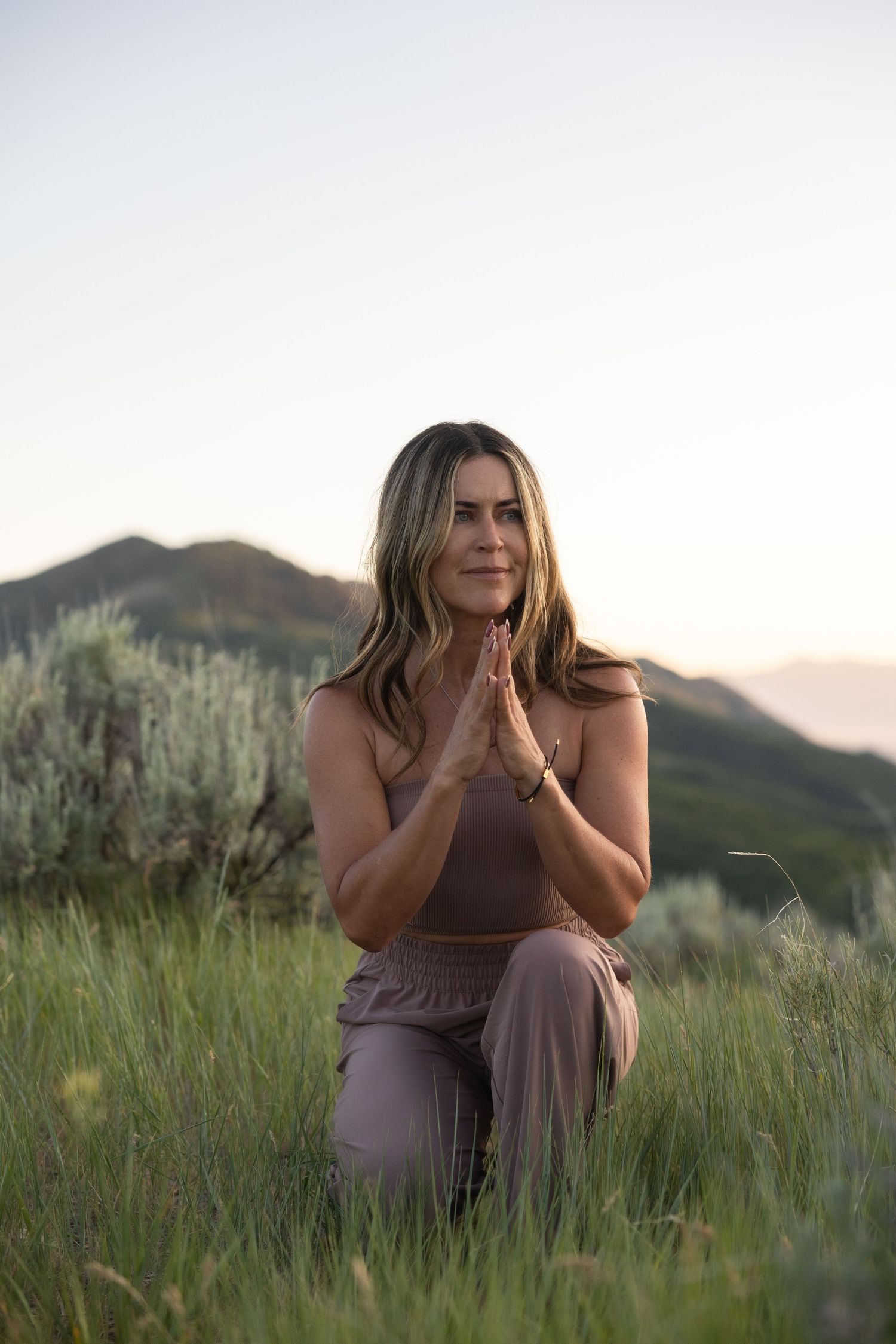 Azure meditates in a meadow with tall grass and golden light portrait.
