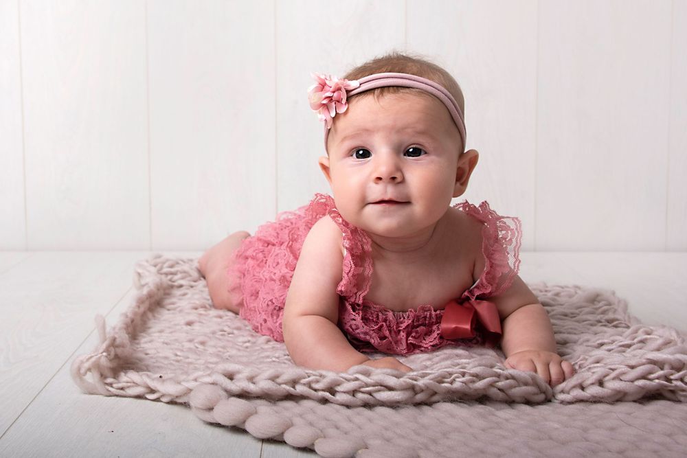Beige knit blanket creates cozy setting for baby milestone photography session.