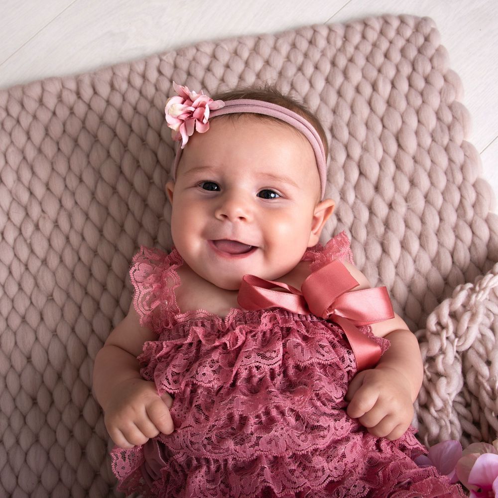 Baby with pink ruffled dress creates sweet milestone portrait setting.